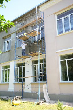 KYIV - UKRAINE, Ekim - 14, 2025: sıva ve boyalı ev dekorasyonu. İnşaat müteahhidi boyamadan önce dış duvarları sıva yapıyor.