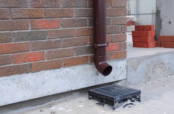 你家的雨水排水沟系统的设计是为了捕捉和去除屋顶上的水 而下喷口则是将水的柱从地基上移开 — 图库照片