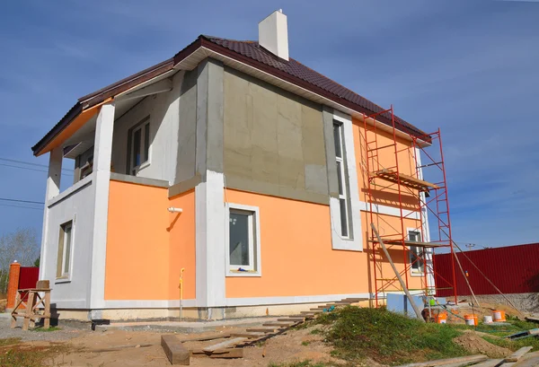 Construction or repair of the rural house with balcon, eaves, windows, chimney, roofing, fixing facade, insulation, plastering and using color. House construction. Royalty Free Stock Photos