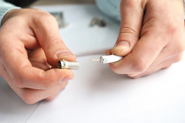 Nahaufnahme der Hände eines Arbeiters und montierter Fernsehanschluss für Koaxialkabel, das in Kabelfernsehanlagen verwendet wird. — Stockfoto