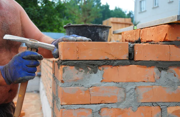 Muraren med en bricklayingen hammare att bygga nya rött tegel Wal — Stockfoto