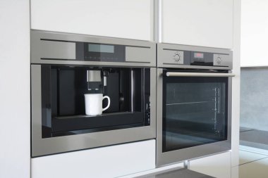 Kahve makinesi, beyaz kahve fincanı ve elektrikli fırın..