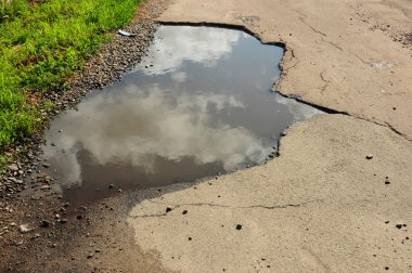 Su birikintisi üzerinde yakın çekim. Pot delik veya çukur bir kırık kırık asfalt kaplama ile otomatik süspansiyonlar için yol bakım ve araba sigorta risk ulaşım sembolü kirli su su birikintisi görüntüsünü.