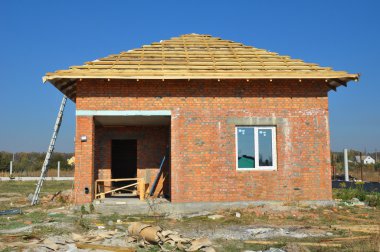 İle çatı kirişleri çerçeveleme yeni çatı Membran Kaplamalar ile ahşap inşaat ev. Çatı inşaat dış kırmızı tuğla ev duvar cephe ile.