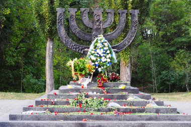 KIEV - UKRAINE, SEPTEMBER - 23, 2015: A menorah memorial with flowers dedicated to jewish people executed in 1941 in Babi Yar in Kiev clipart