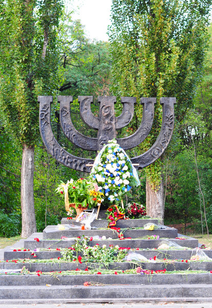 KIEV - UKRAINE, SEPTEMBER - 23, 2015: A menorah memorial with flowers dedicated to jewish people executed in 1941 in Babi Yar in Kiev. Holocaust. 100000-150000 people were killed at this place.
