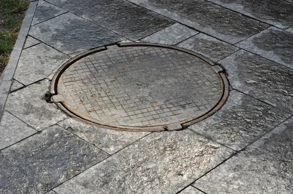 Nahaufnahme von Kanaldeckel auf Gartenpflaster — Stockfoto