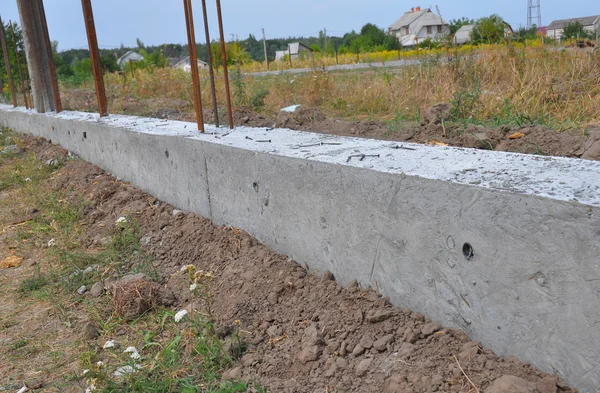 Close up on building concrete foundation for new fence with metal supports. Construction site during concrete pouring works with formwork. — Stock Photo, Image