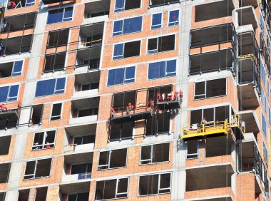 Etüt büyük inşaat alanında. İşçiler bina yeni konut, Windows, duvar izolasyonu, balkon yükleyin. Sanayi Yapılar İnşaat
