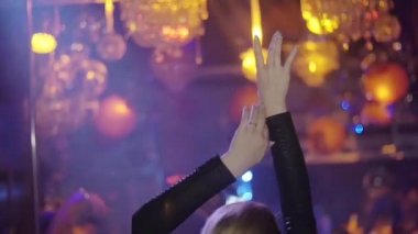 Back side Dj girl raise both hands, dance at turntable in nightclub. Slow motion