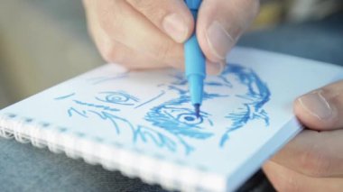 Dostum el yüz kağıt defter odakta üzerinde mavi marker tarafından boya. Bir gün. Yakın çekim