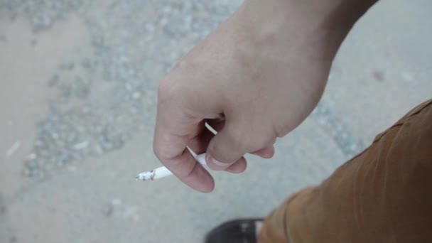 Muž ze vnitřku cigaretový popel na asfaltu zaměření. Ulice. Letní den. — Stock video