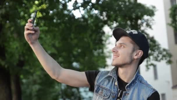 Young man in cap take several selfie on phone. Summer day. Smiling. Emotion — Stock Video