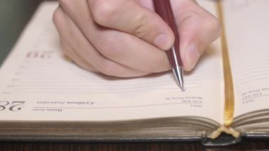 Sağ el yazma word iş üstünde kağıt defter bir kalem tarafından mans. Yakın çekim