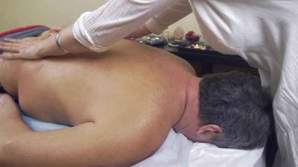 A massagista faz a massagem terapêutica da espinha dorsal ao homem gordo adulto. Tiro médio . — Vídeo de Stock