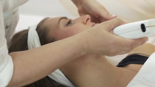 Il primo piano di mani cosmetologist mette la cera a guance, il mento di ragazza in salone di bellezza — Video Stock