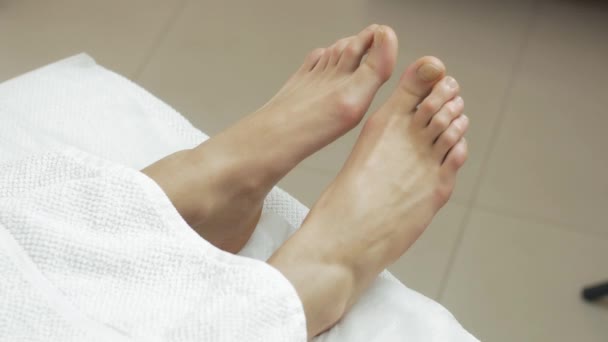 No mover los pies de mujer debajo de una manta blanca en un salón de belleza. Paciente. — Vídeos de Stock