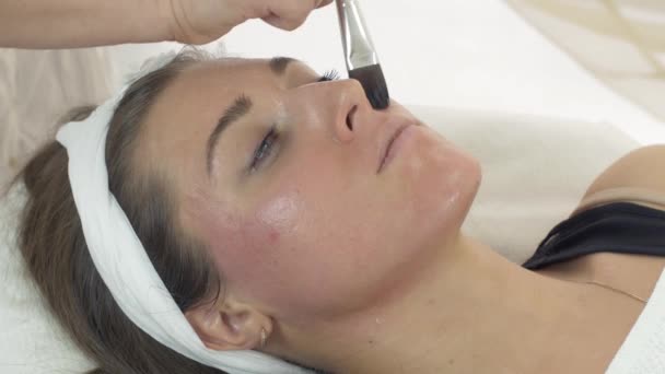 Close up van de handen van de schoonheidsspecialist zetten bevochtigen op meisje gezicht in beauty salon. — Stockvideo