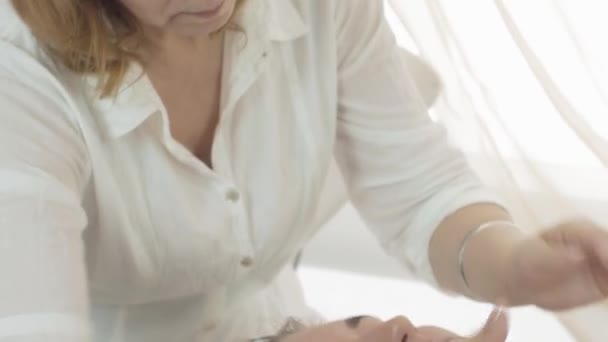 Close up manos cosmetólogas poner crema humectante en la cara de chica en salón de belleza — Vídeo de stock