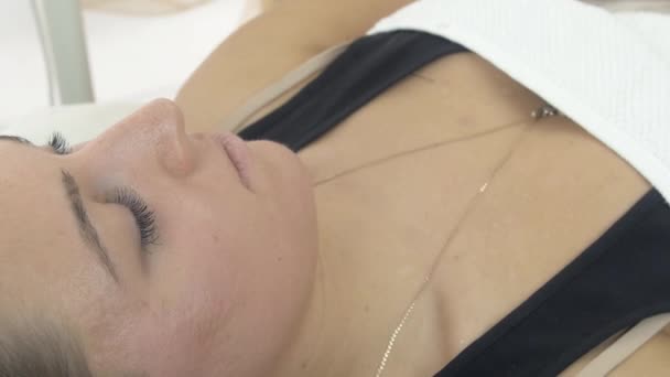 Close-up de rosto menina mentira sob cobertor no salão de beleza em procedimentos cosméticos . — Vídeo de Stock