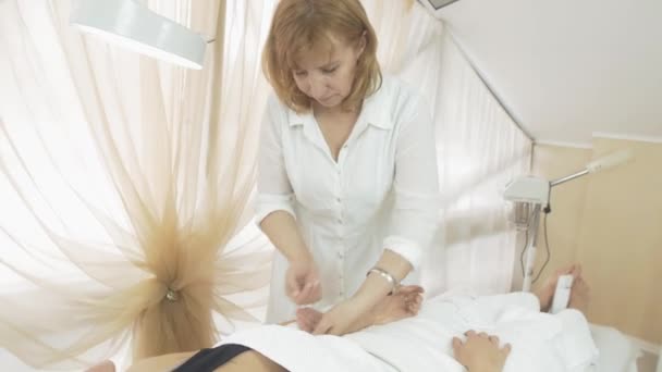 Kosmetolog vaxning vänster hand av flicka i beauty saloon av remsor. Medellång skott — Stockvideo