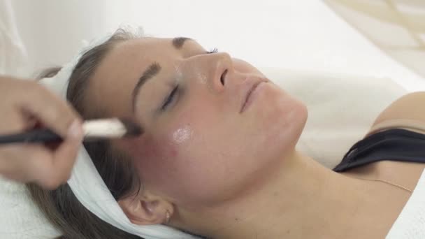 Close up van de handen van de schoonheidsspecialist moisturizer zetten meisje gezicht in beauty salon. — Stockvideo