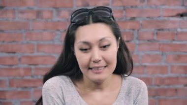 Siyah uzun saçları yetişkin kız utangaçlık kamera tasvir. Döküm. Tuğla duvar