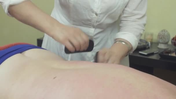 Masseurin macht heilende Steintherapie-Massage von Rücken zu dicker Frau im Salon. — Stockvideo
