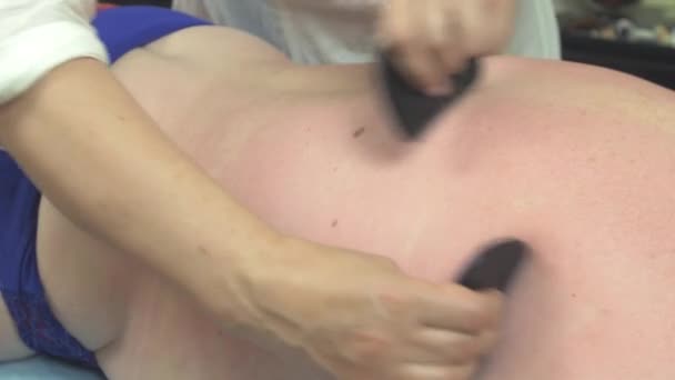 Masseuse make stone therapie massage van rug naar dikke vrouw in salon. Aaien — Stockvideo