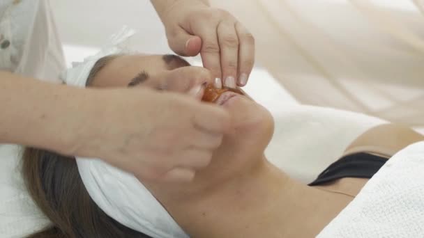 Professionell kosmetolog sätta shugaring ovanför läppar flicka i skönhetssalongen. — Stockvideo