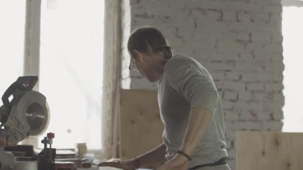 Aged carpenter in glasses checking wooden board after polishing. Manufacturer — Stock Video