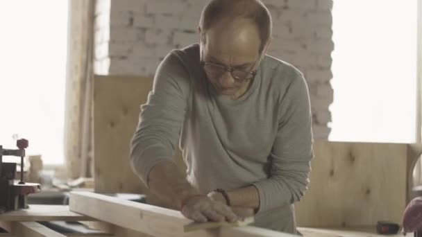 Adulto carpintero pulir la superficie del tablero de madera por esponja especial. Fabricante — Vídeo de stock