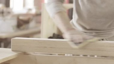 Woodworker polish surface and edge of long wooden board by sponge. Manufacturer