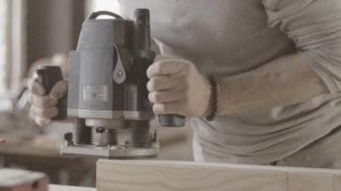 Woodworker treats long wooden board on edge by plunge router. Manufacturer