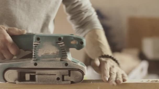 Professional joiner treat wooden board by belt sander. Smooth movements — Stock Video