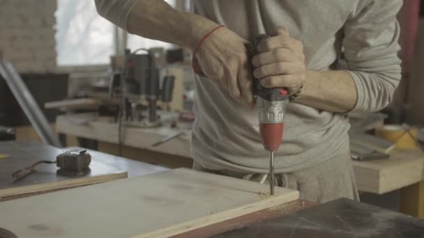 Professionele leeftijd timmerman Maak gaatjes in gepolijst houten plank door boor. Scobs — Stockvideo