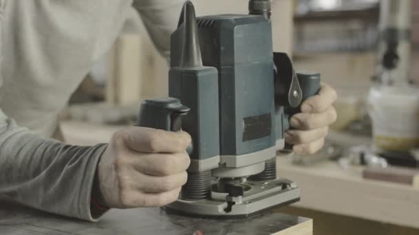 Woodworker treats corner, edge wooden board by plunge router. Manufacturer. — Stock Video