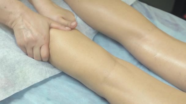 Masseuse make relaxing massage of right leg, ankle to woman in saloon. Stroking — Αρχείο Βίντεο