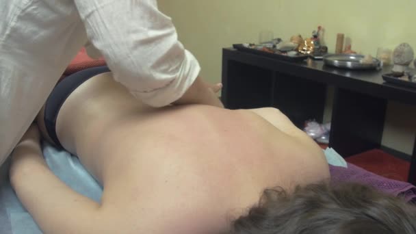 Masseuse make therapeutic massage of left back side to young woman in saloon. — Stock Video