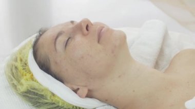 Woman face with closed eyes in beauty saloon with problem aged skin. Acne.