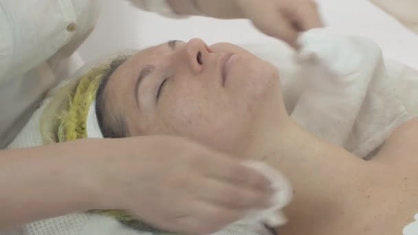 Cosmetologue effacer femme visage par serviettes après masque dans le saloon. Problème de peau — Video