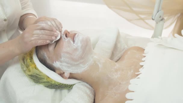 美容サロンで綿のパッドで女性の顔を粘土マスク一掃美容師 — ストック動画