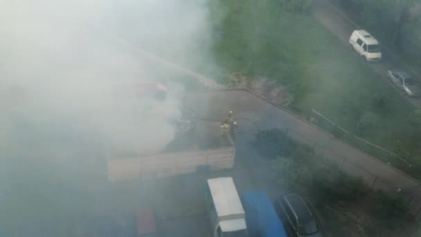 A vista em bombeiros extingue o fogo na jarda do edifício de arranha-céus. Muito fumo. Noite de verão — Vídeo de Stock