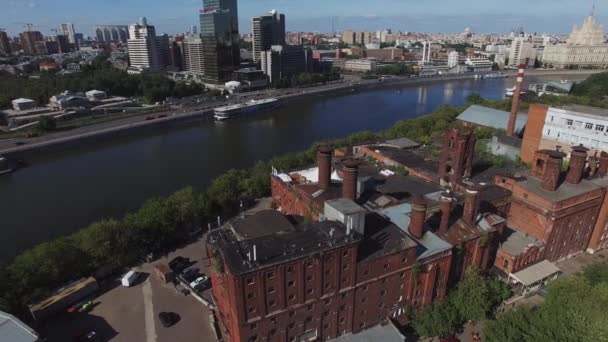 Квадрокоптер літає навколо старих цегляних будівель з трубами в місті на річці. Літній сонячний день . — стокове відео