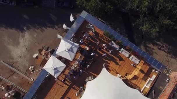 Quadrocopter atirar restaurante de verão com tenda branca no telhado do edifício. Ensolarado. Gente. Árvores — Vídeo de Stock