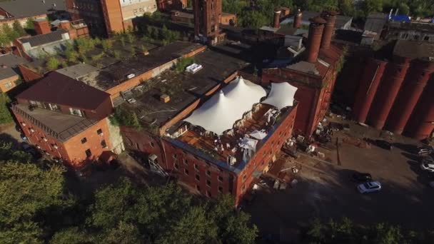 Quadrocopter shoot restaurant avec des tentes blanches sur le toit de vieux bâtiment en brique. Journée ensoleillée. Les gens — Video