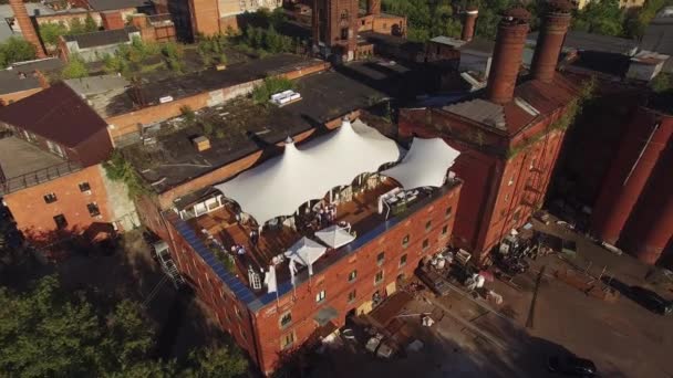 Quadrocopter schießen Sommerrestaurant mit weißen Zelten auf Dach eines alten Gebäudes in der Stadt. Sonnig. Menschen — Stockvideo