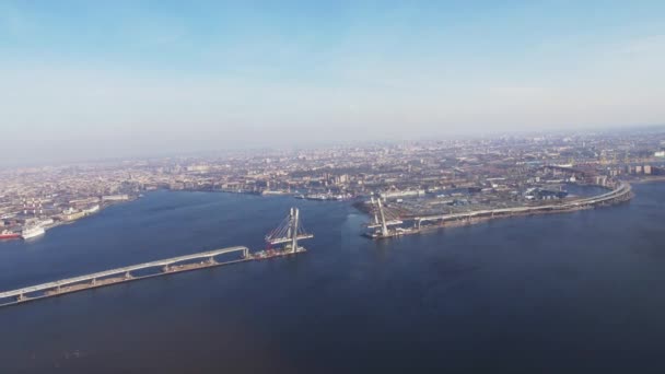 Pemandangan udara dari helikopter terbang di atas sungai. Tinggi. Megapolis di pantai. Jembatan sedang dibangun . — Stok Video