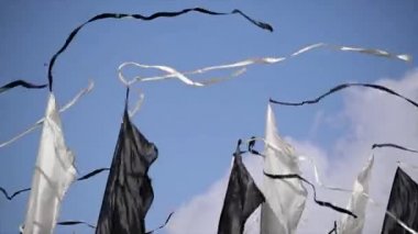 Siyah ve beyaz bayrakları uzun şeritler ile yaz günde rüzgarla sway. Mavi açık gökyüzü. Festivali. Ağaçlar