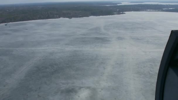 Luchtfoto van de helikopter vliegen boven bevroren meer op groene bossen. Camera binnen. Ijswater oppervlak — Stockvideo